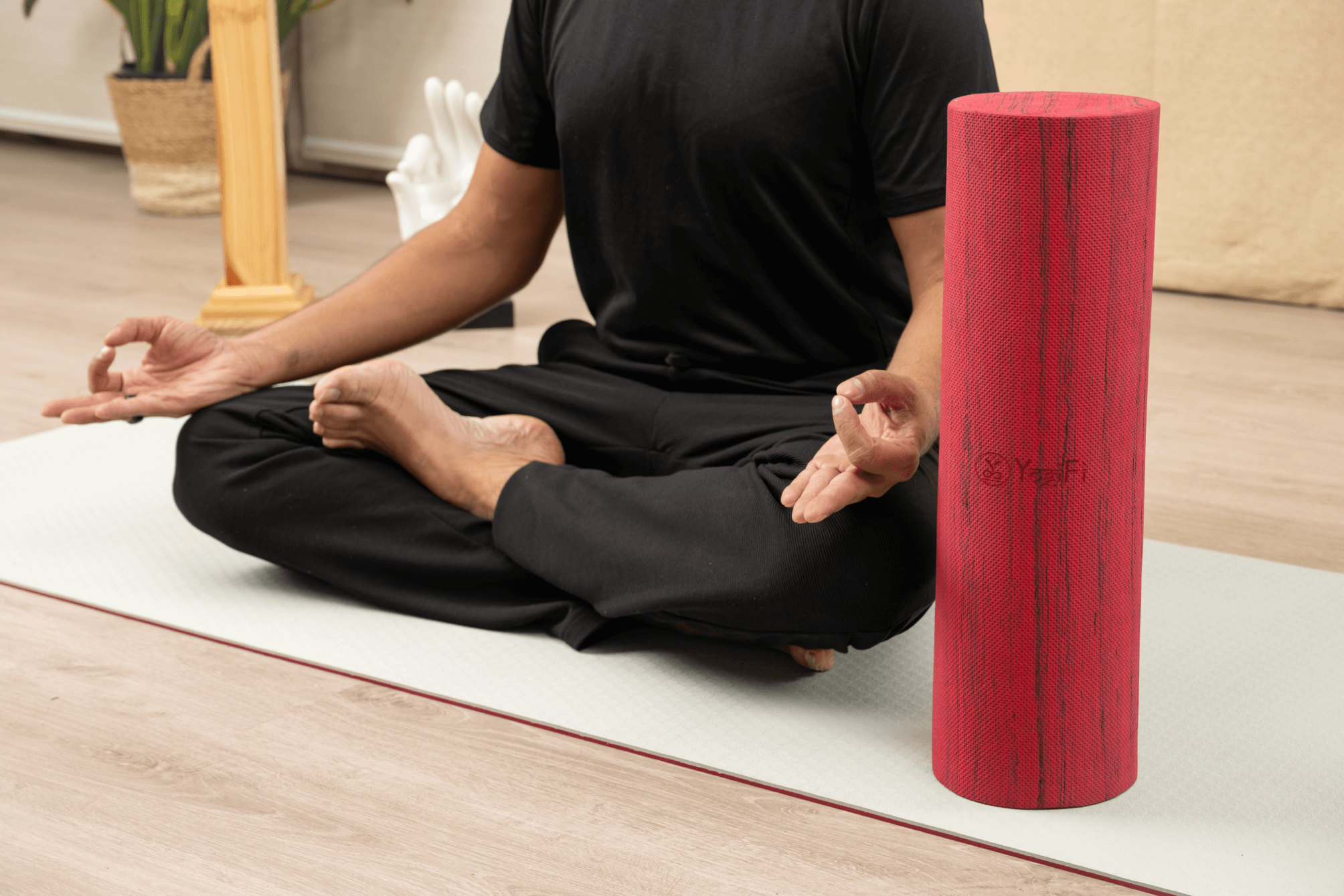 Bright red yoga roller positioned on a mat, ready for use.