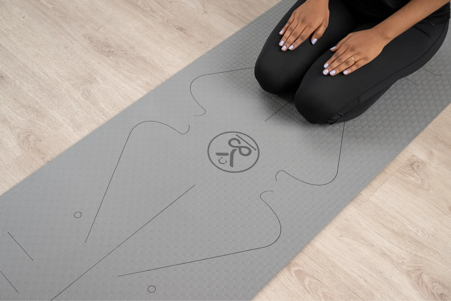 Stylish grey yoga mat laid out on a wooden floor, ready for practice.