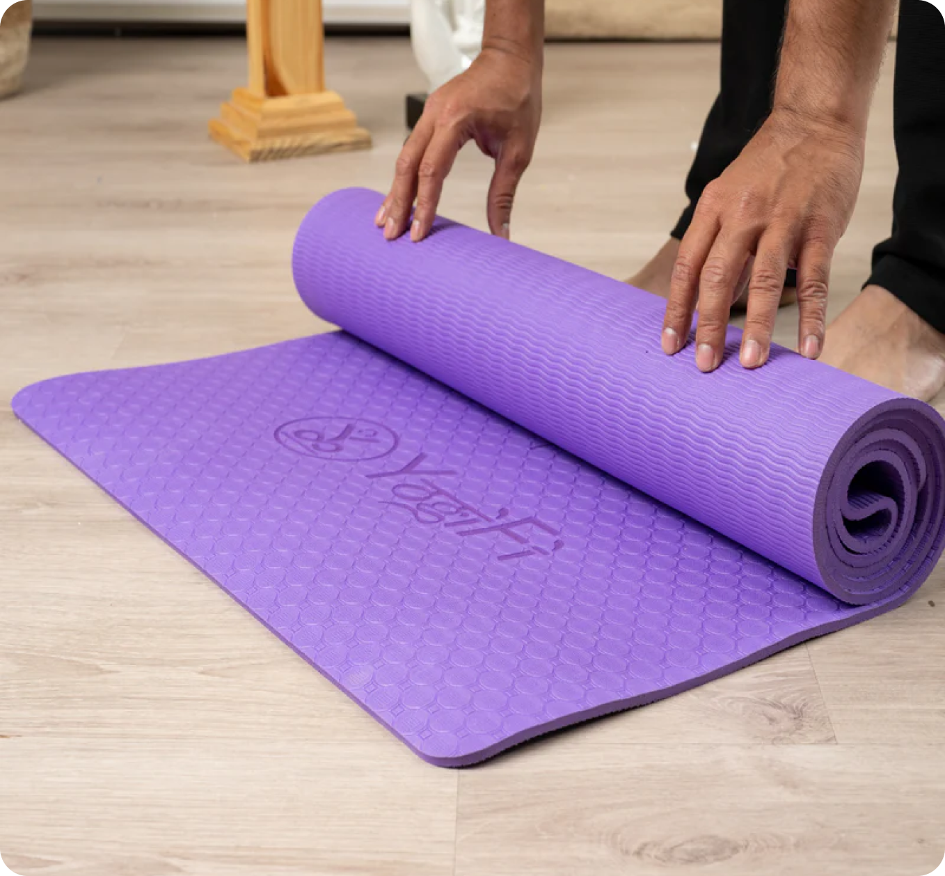 Vibrant purple yoga mat laid out on a wooden floor, ready for practice.